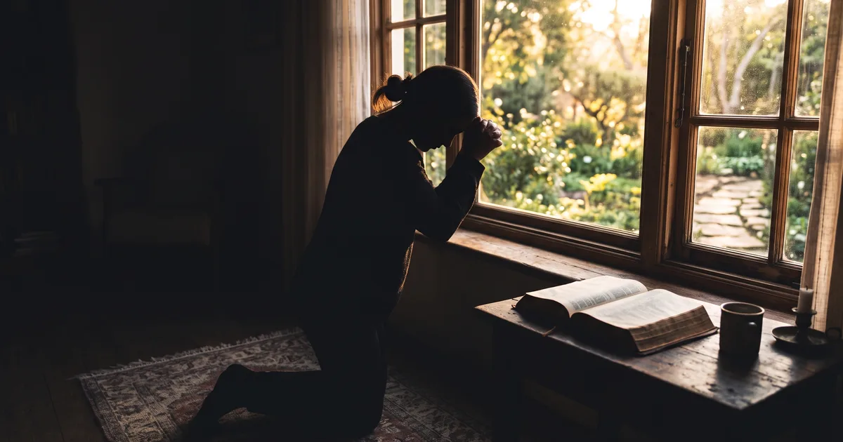 Silueta orando ventana leyendo la Biblia